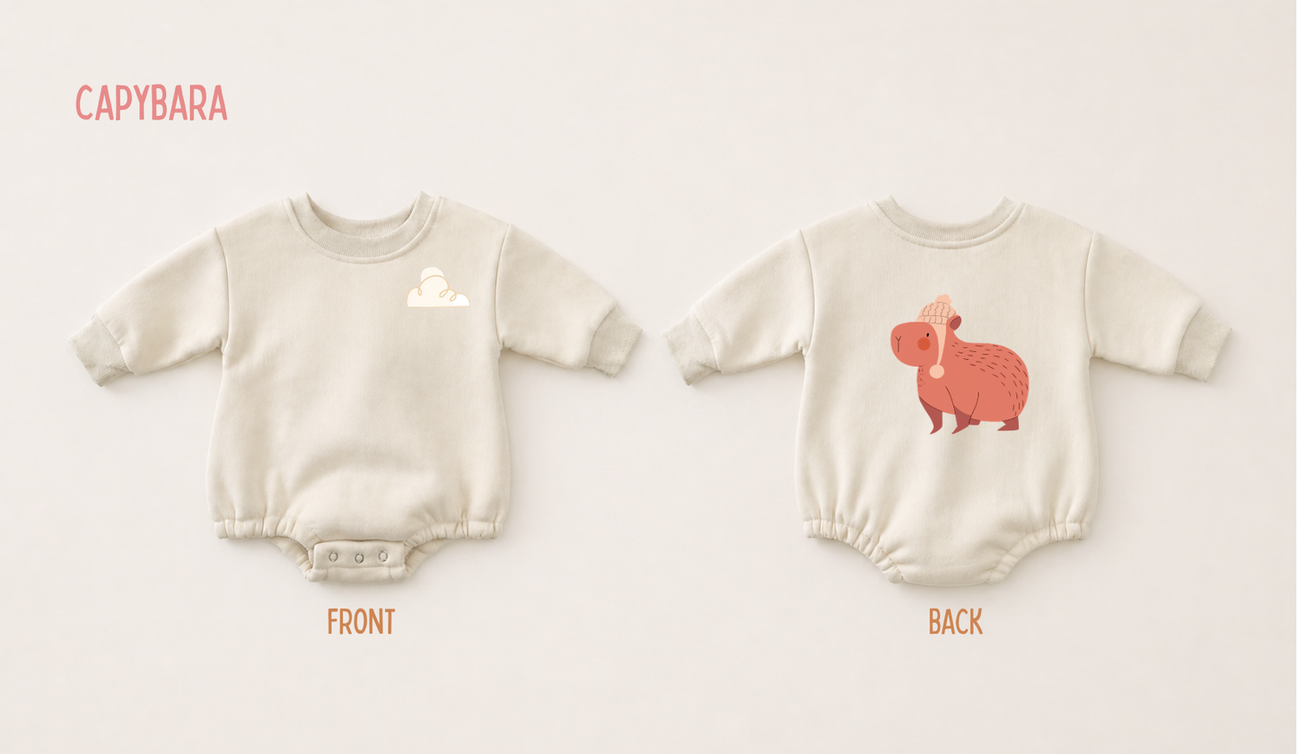 Front and back view of a cream fleece baby romper featuring a playful capybara print on a soft neutral background.