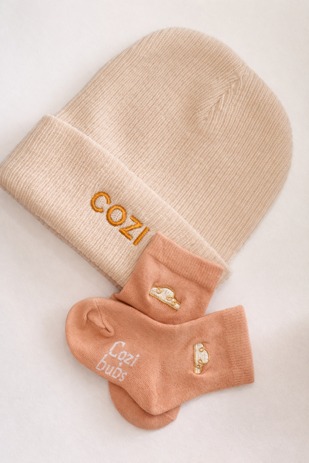 Beige beanie and socks with 'Cozi' branding on a light background
